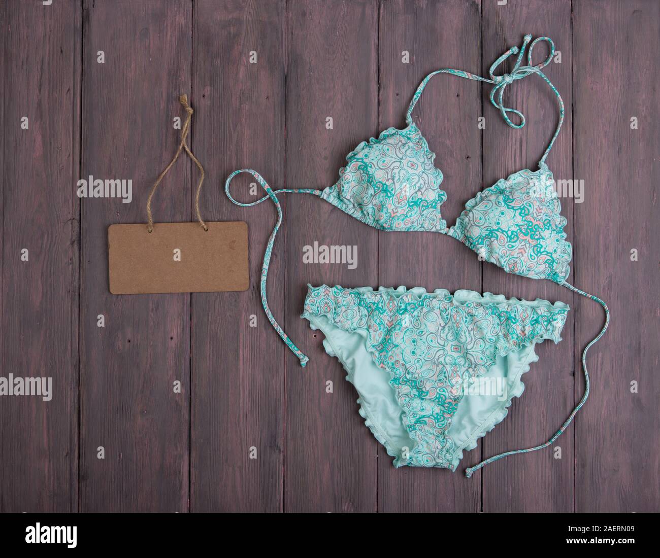 Sea holidays / travel concept - blue beautiful swimsuit in ornament and blank blackboard on wooden background Stock Photo