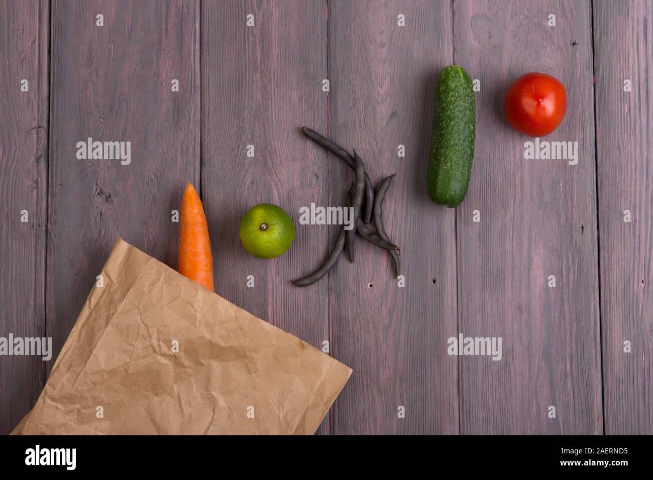 Healthy vegetarian food concept - paper eco bag with various vegetables on wooden table Stock Photo