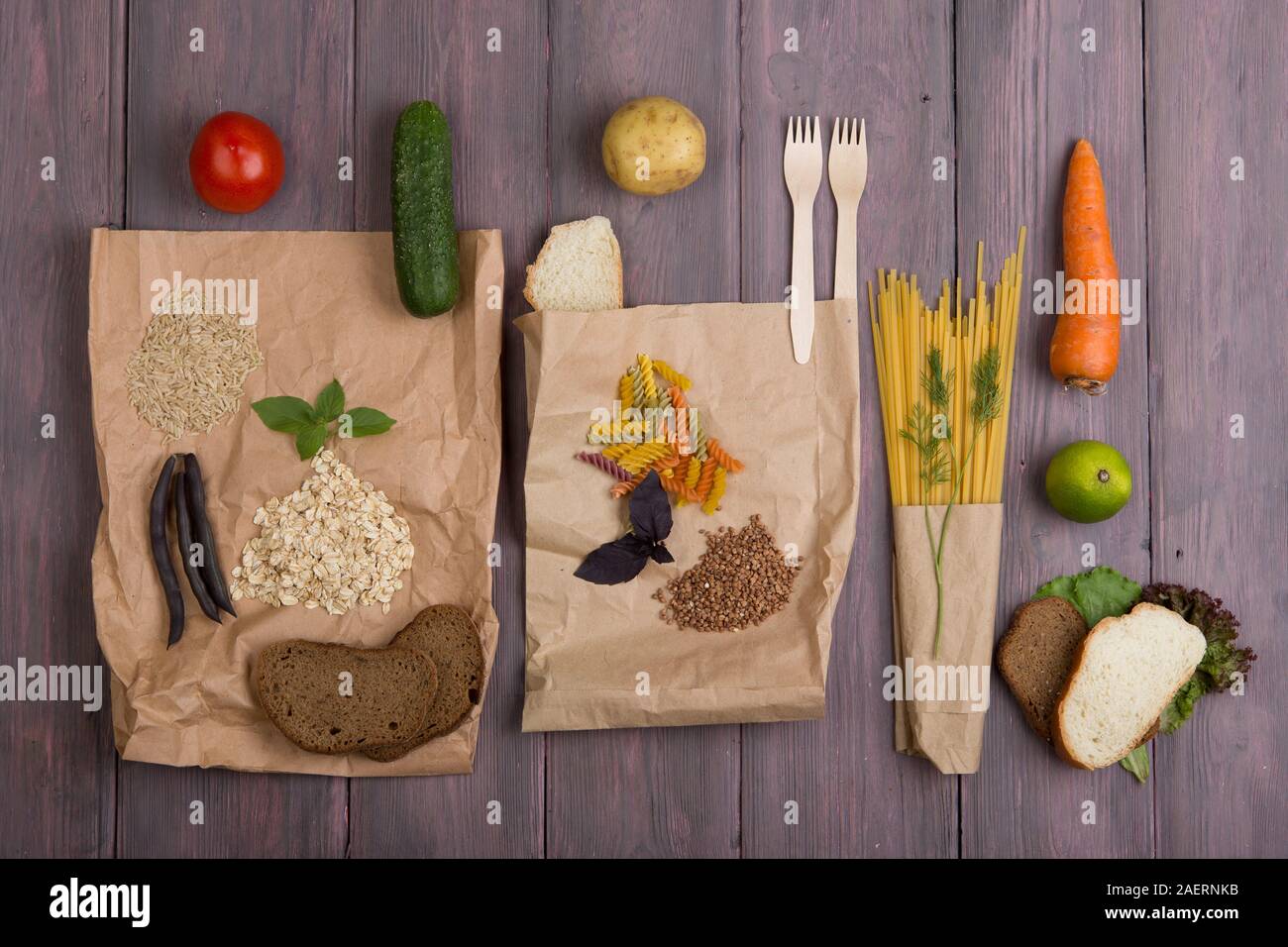 Eco bags with products rich of complex carbohedrates: cereals, bread, pasta and vegetables on wooden table Stock Photo