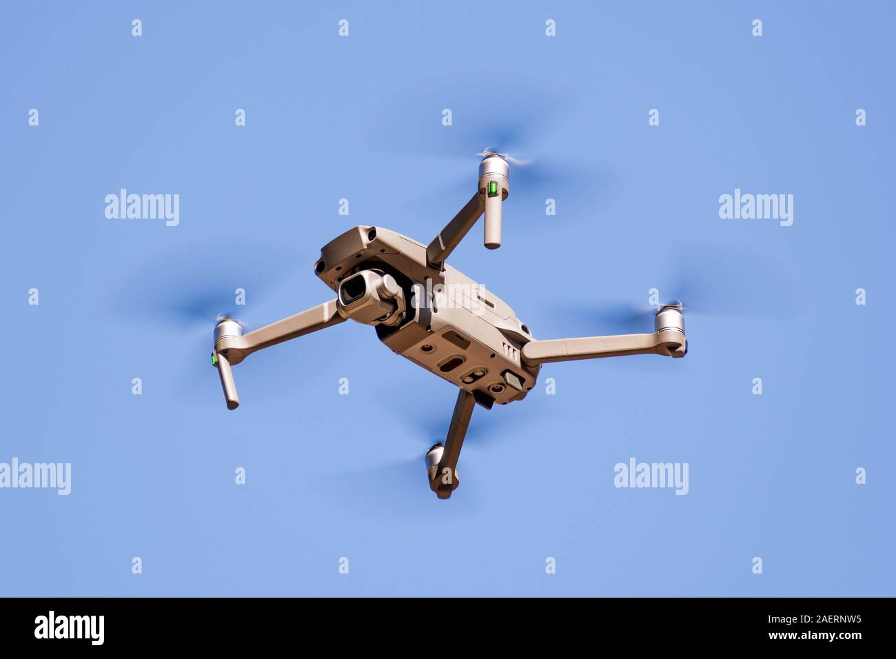 Close up of flying drone quad-copter with digital camera; blue sky background Stock Photo