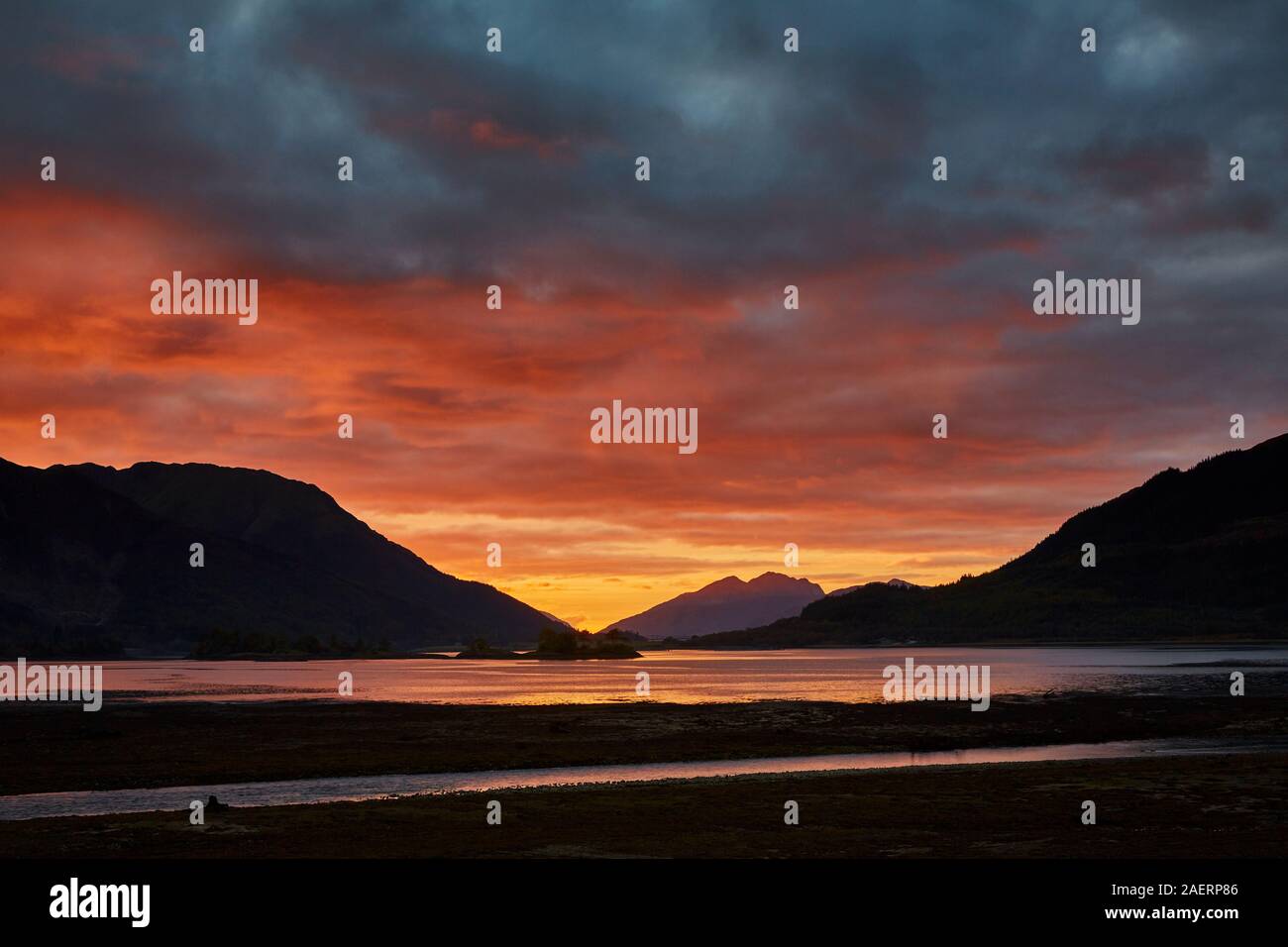 A spectacular sunset over Loch Leven during an autumn evening with the colours of the clouds reflecting in the water and the mountains in silhouette Stock Photo