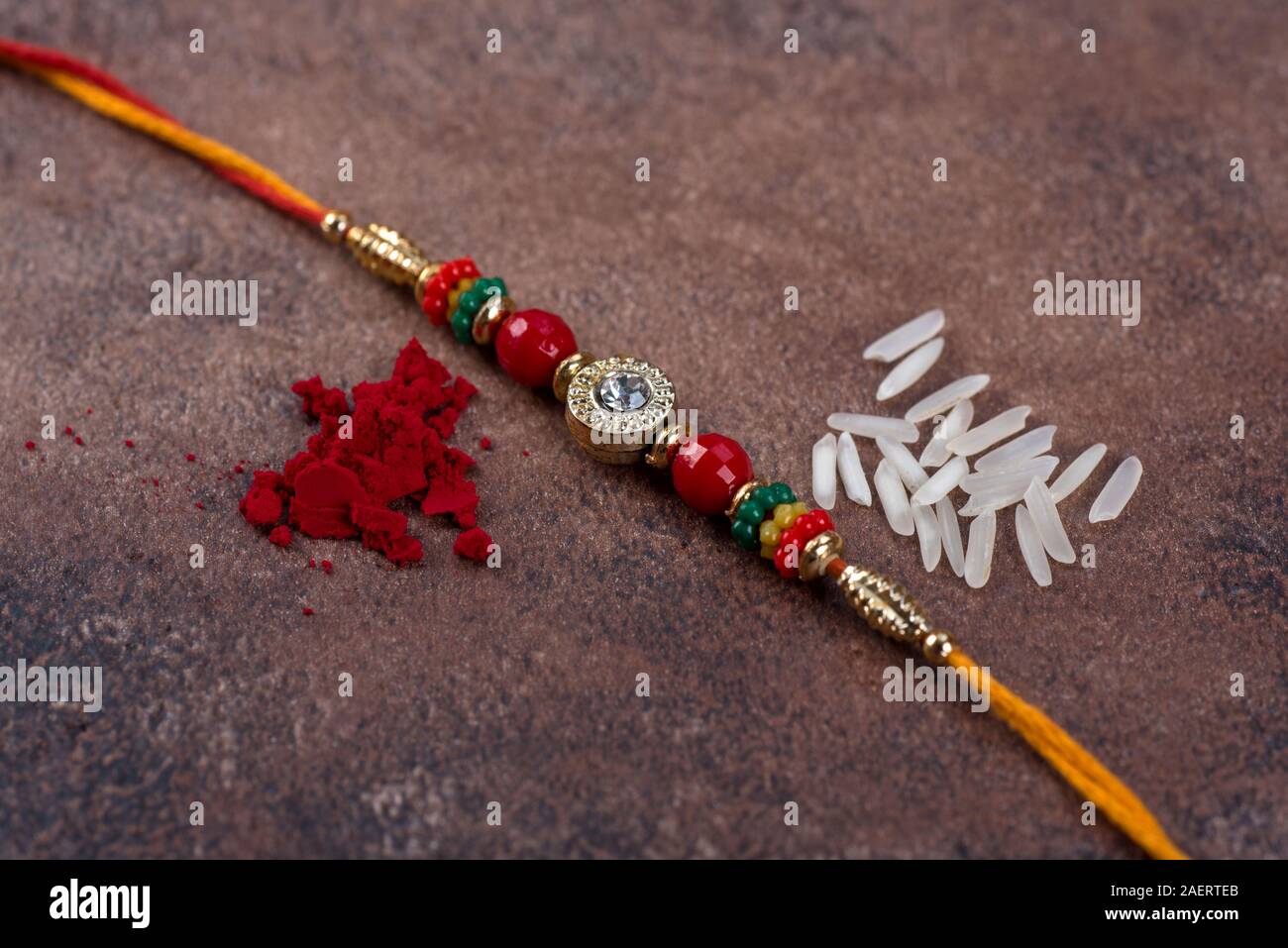 Raksha Bandhan : Rakhi with rice grains and kumkum on stone background ...
