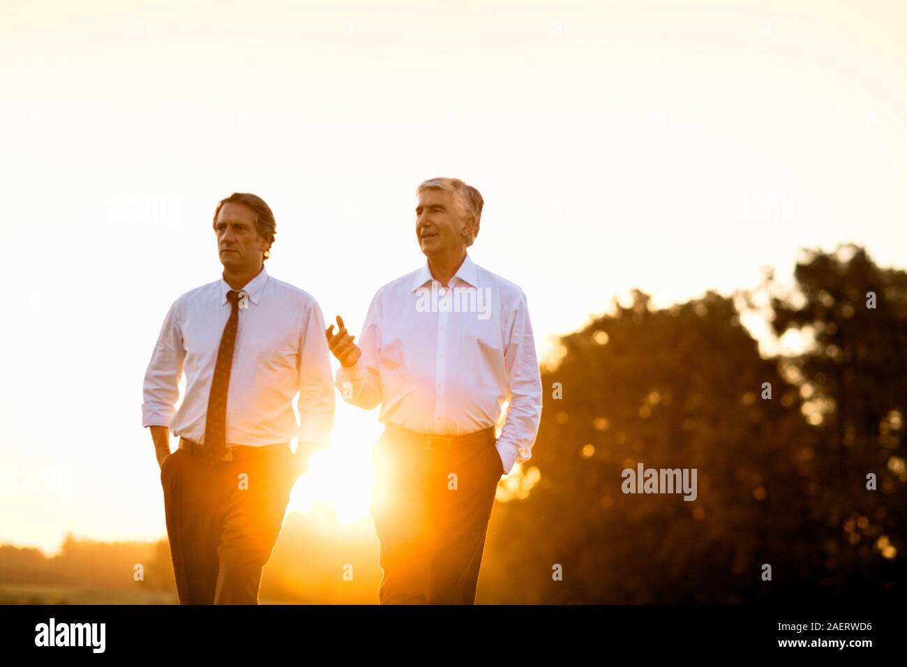 Two businessmen on a break talk as they walk side by side through a ...