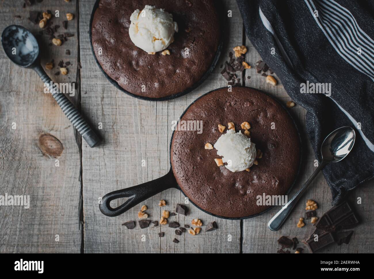 Top view of brownies with ice cream and nuts in cast iron skillets. Stock Photo