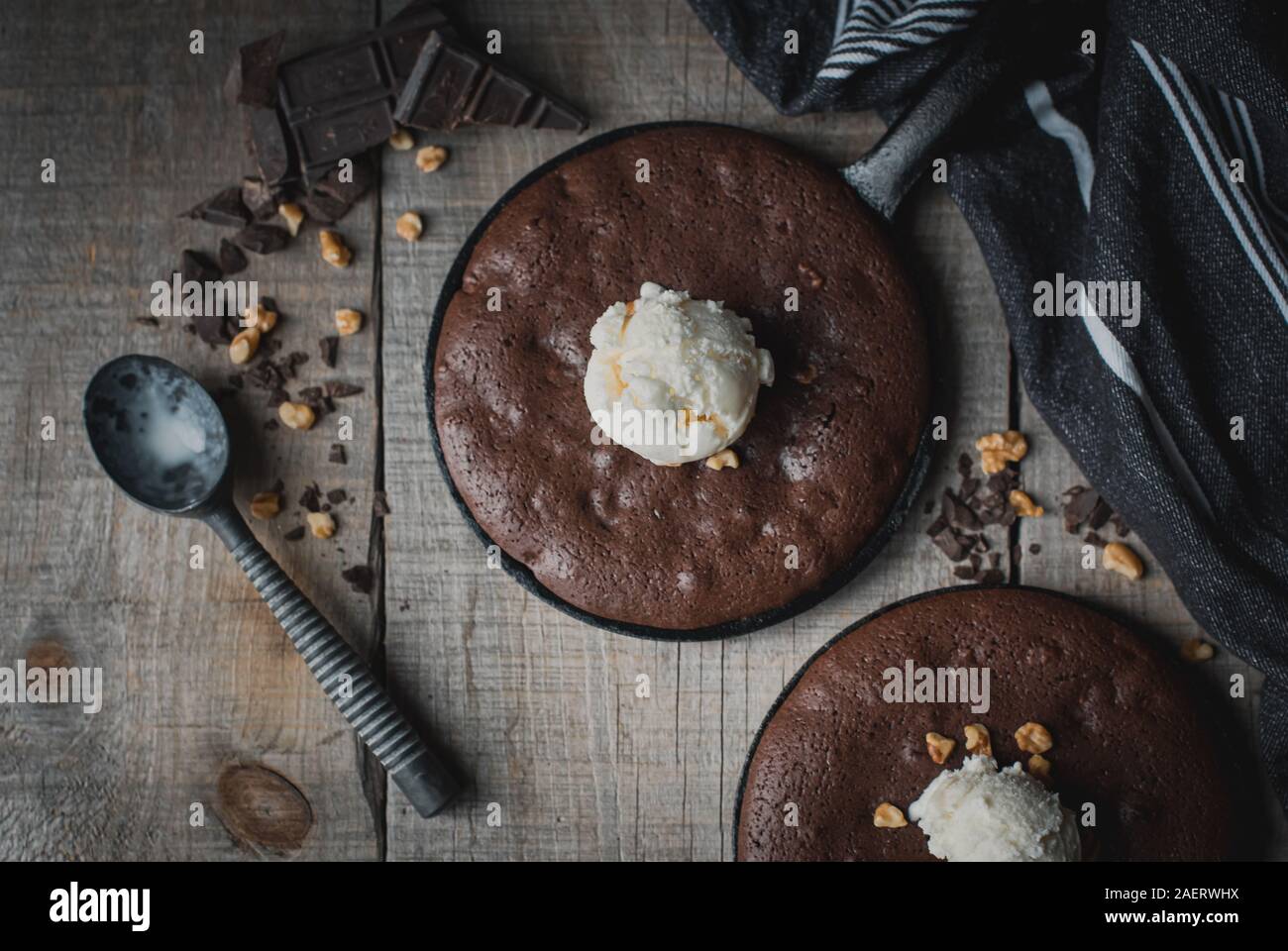 Top view of brownies with ice cream and nuts in cast iron skillets. Stock Photo