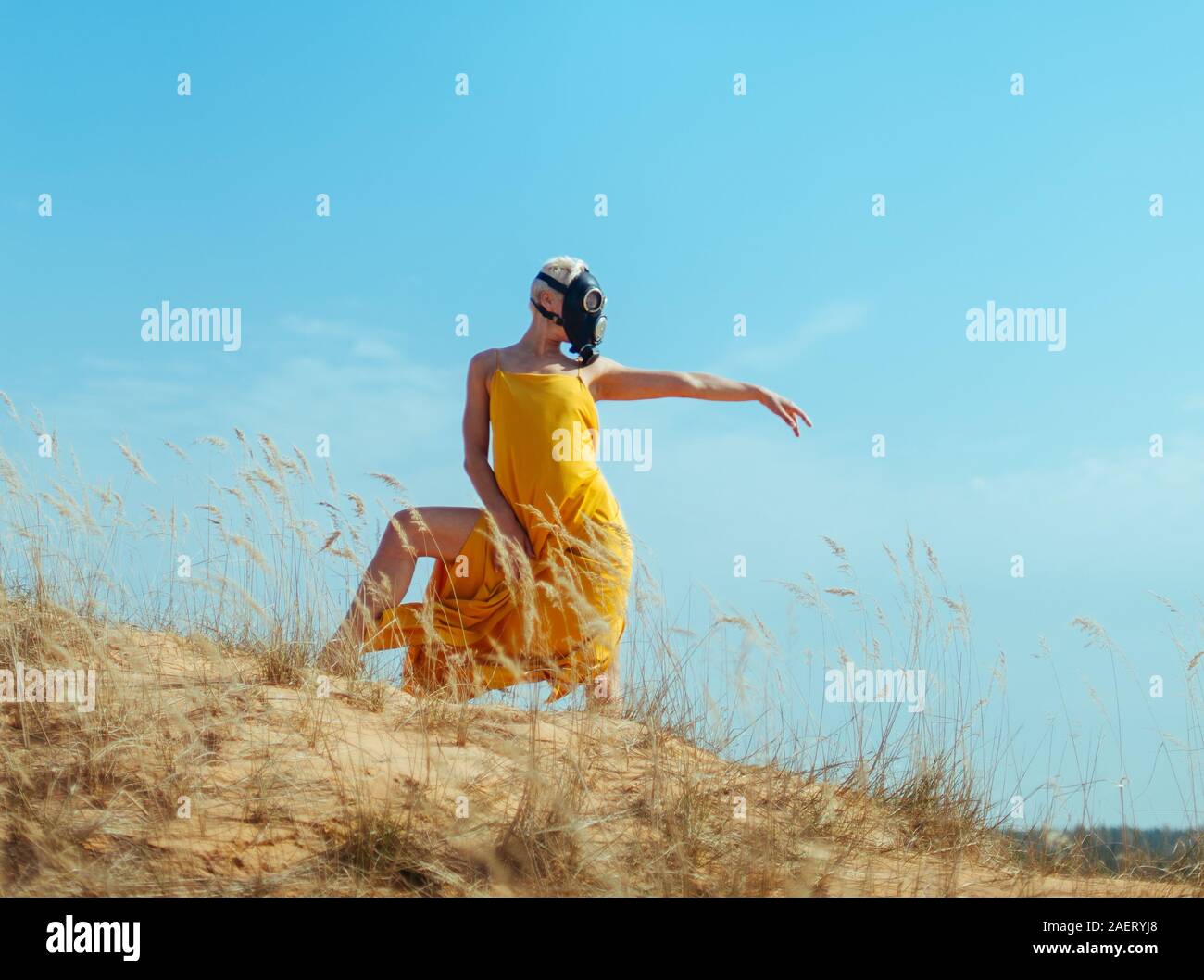 Girls in yellow dress and Gasmask dancing on the sand dunes Stock Photo
