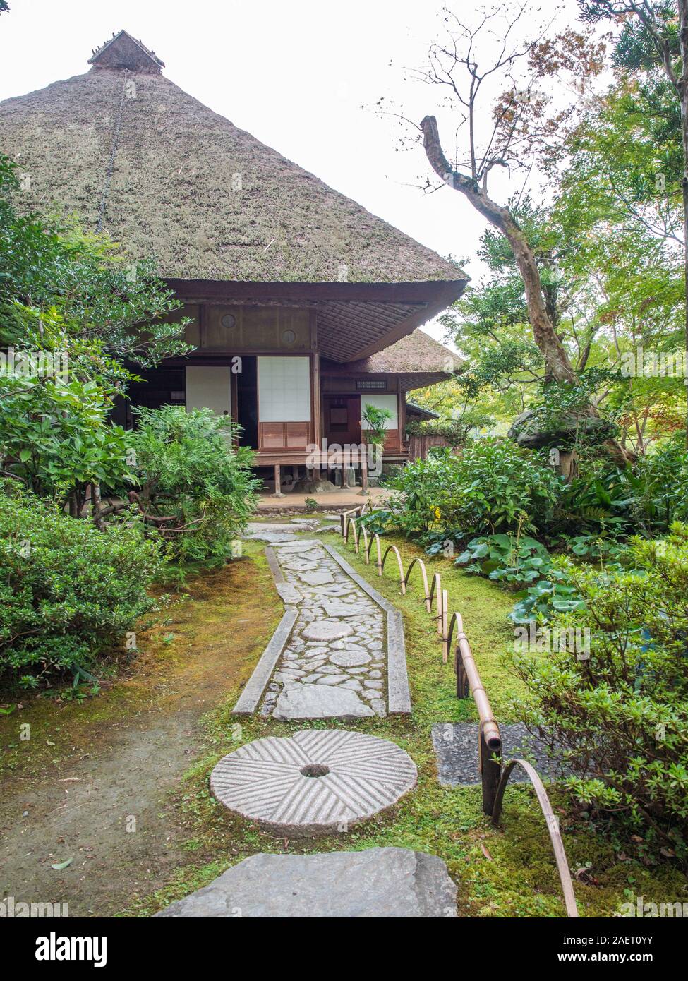 Japanese garden, moss covered ground, stepping stone pathway, curved bamboo fence,  thatched roof, Garyuin, Garyusanso, Ozu,  Ehime,  Shikoku, Japan Stock Photo
