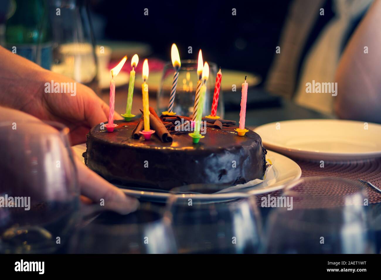 A portrait of a person putting a chocolate birthday cake with burning