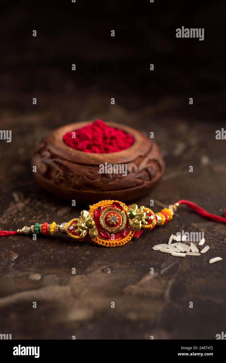 Raksha Bandhan background with an elegant Rakhi, Rice Grains and Kumkum ...