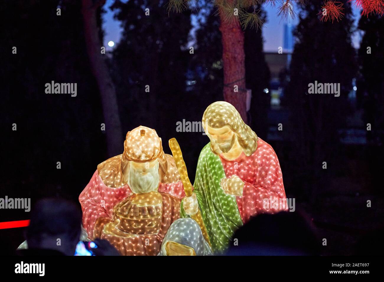 People crowd around a nativity scene featuring a wise man, Mary, and Joseph at Torrejon de Ardoz Christmas Fair Stock Photo