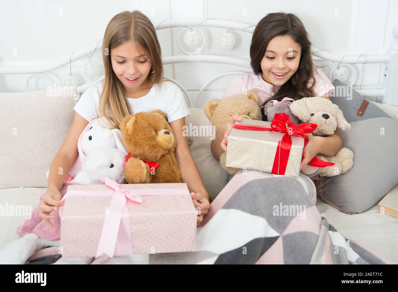 Birthday surprise. Surprised kids. Birthday girls. Happy children receive birthday gifts in bed. Enjoying their birthday presents. Gift exchange. Holiday celebration. Stock Photo