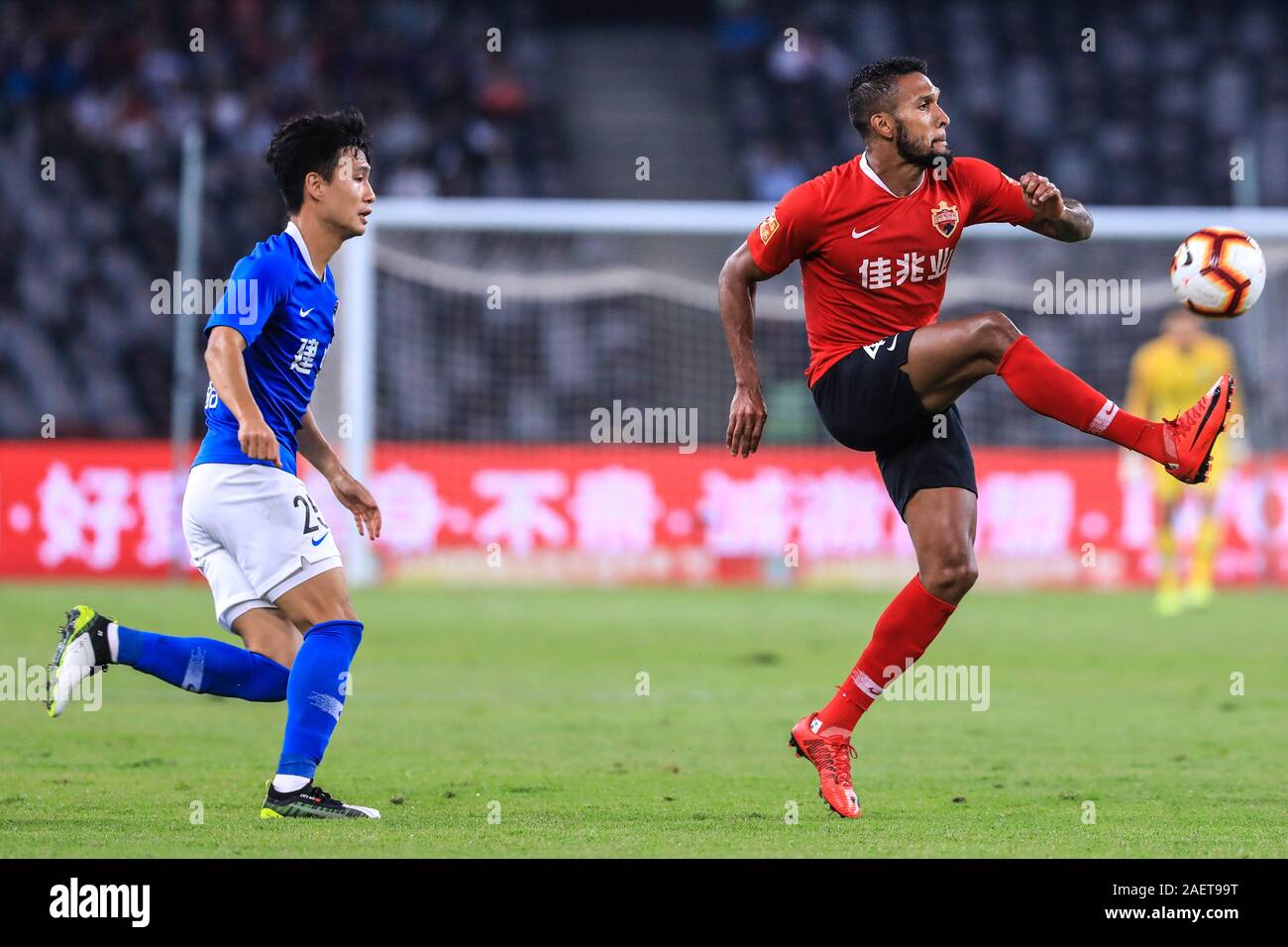 Brazilian-born Portuguese football player Dyego Sousa of Shenzhen F.C., right, passes the ball during the 29th round match of Chinese Football Associa Stock Photo