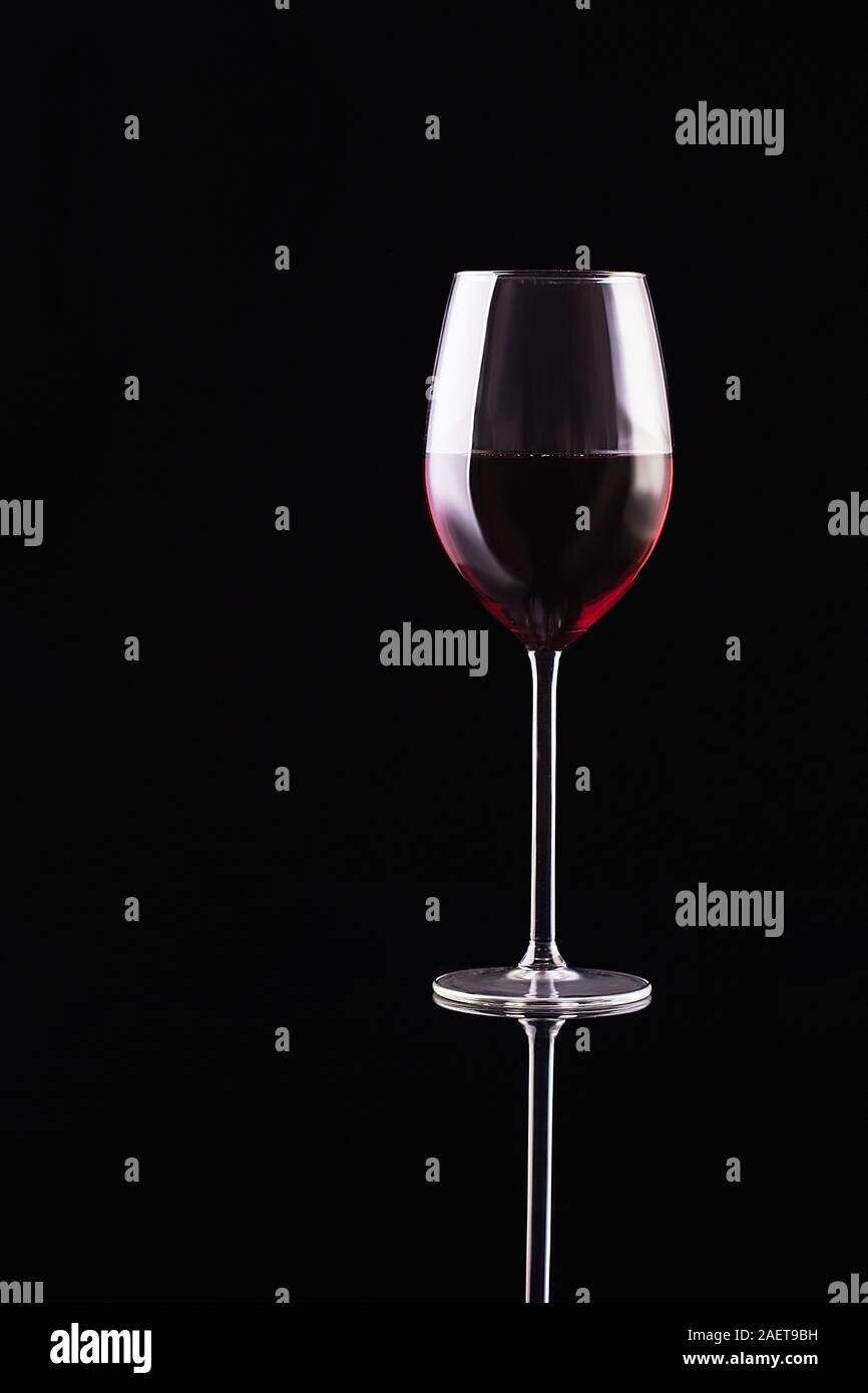 Glass of red wine on black background. Aromatic wine. Strict style