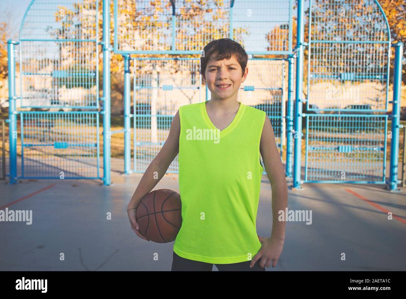 Teenage boy holding a basketball on a court Stock Photo - Alamy