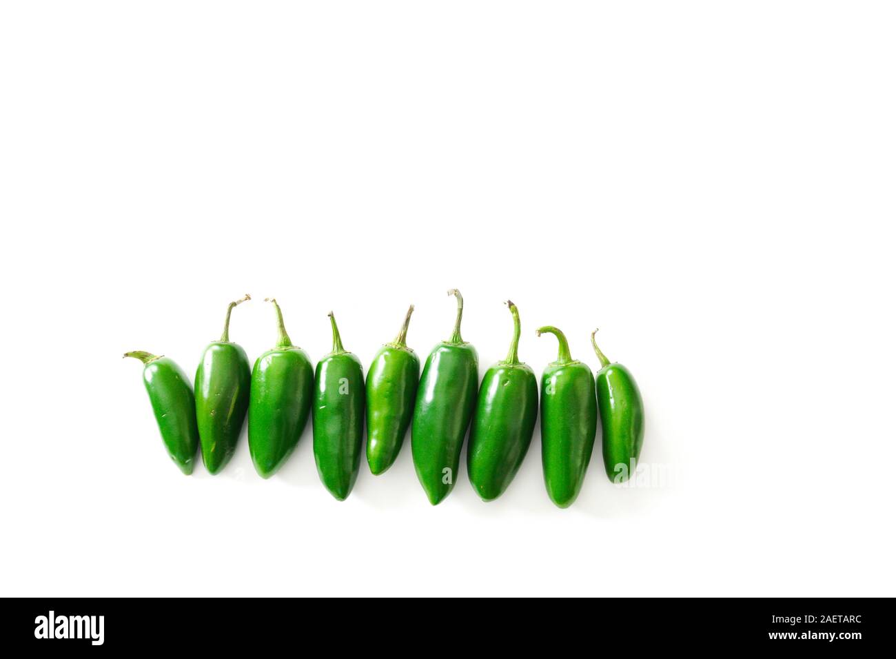 A row of bright green jalapeno peppers isolated on a white background with copy space; food preparation Stock Photo