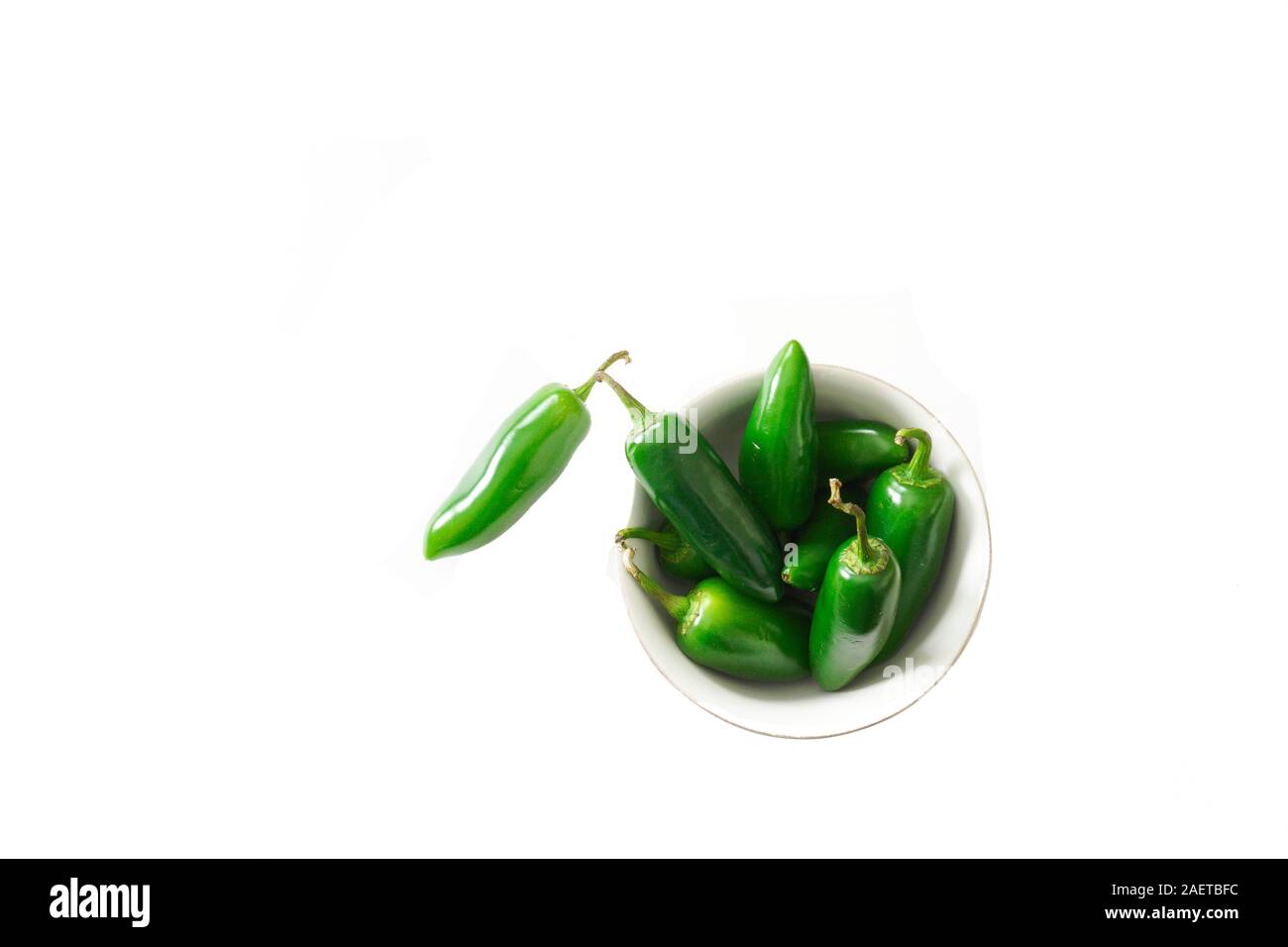 A bowl of bright green jalapeno peppers on a white background isolated with copy space; food preparation Stock Photo
