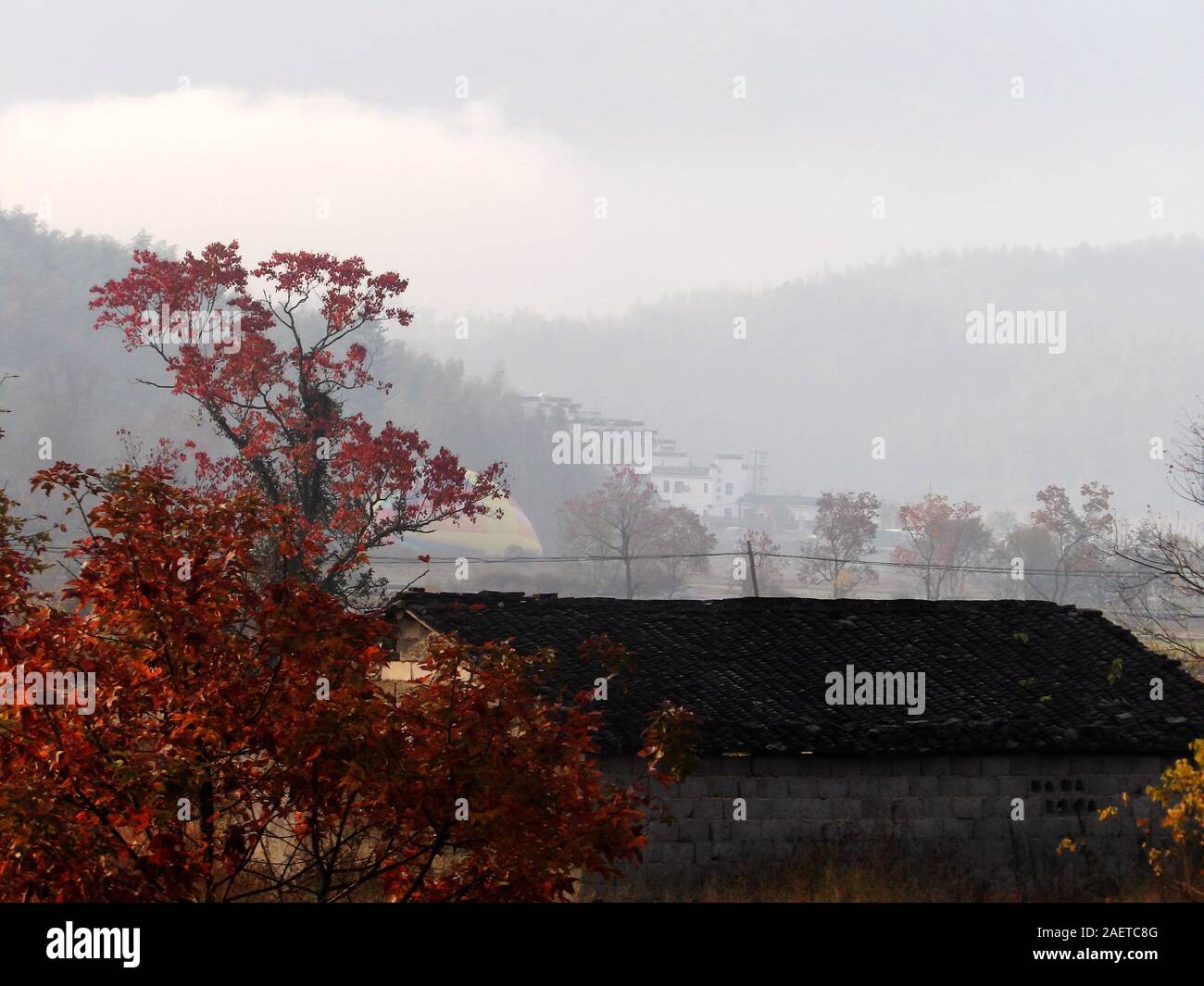 A view of traditional village with red leaves and Hui-style buildings in the mist in Tachuan village, Yi county, Huangshan city, east China's Anhui pr Stock Photo