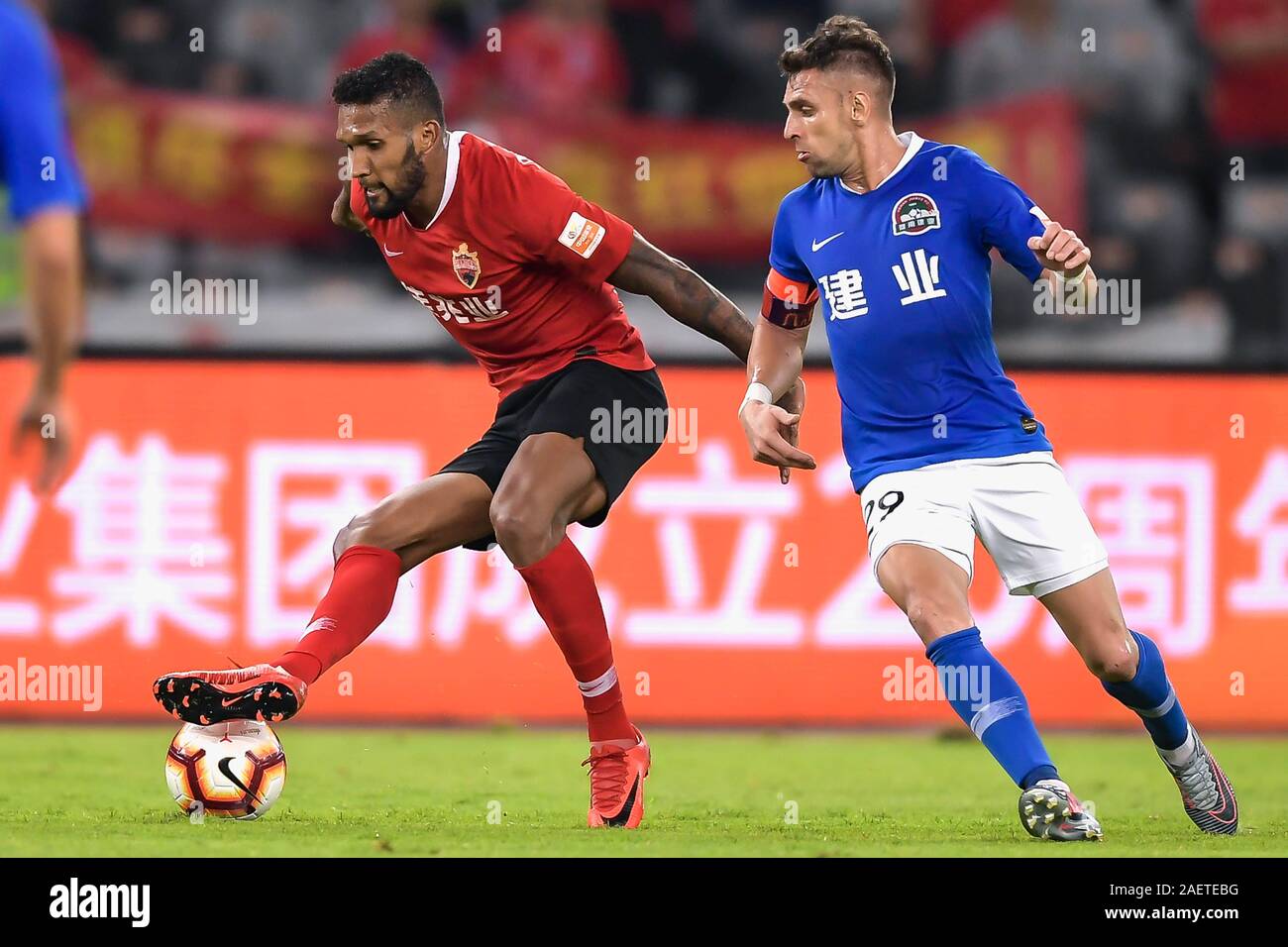 Brazilian-born Portuguese football player Dyego Sousa of Shenzhen F.C., left, keeps the ball during the 29th round match of Chinese Football Associati Stock Photo