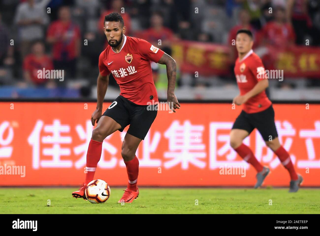Brazilian-born Portuguese football player Dyego Sousa of Shenzhen F.C., left, keeps the ball during the 29th round match of Chinese Football Associati Stock Photo