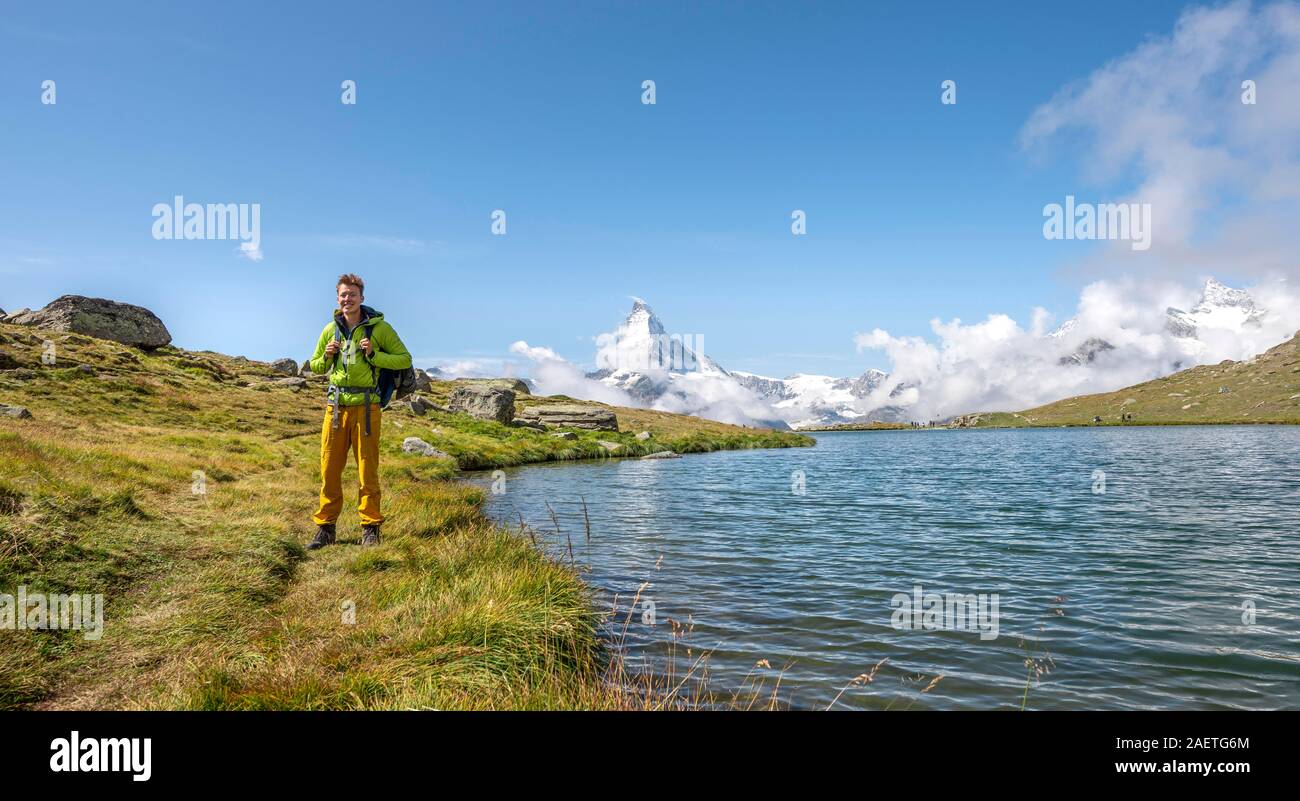 Hiker at Lake Stellisee, 5 lakes Hiking trail, snow-covered Matterhorn at the back, Valais, Switzerland Stock Photo