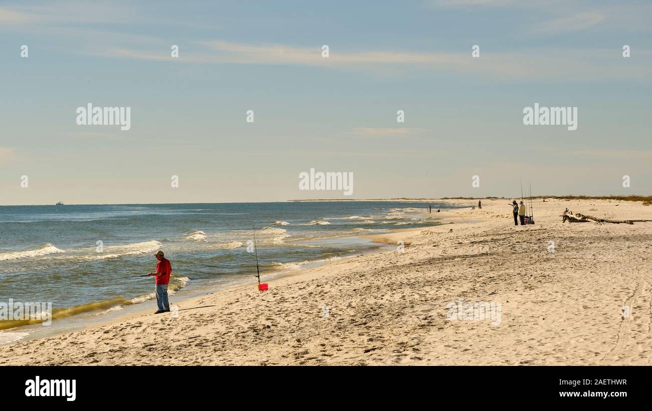 People fishing and walking along the vast Gulf of Mexico beach on Dauphin Island Alabama, USA. Stock Photo