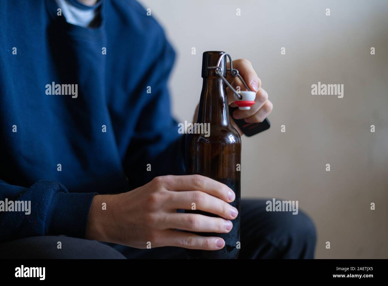 man holding the glass bottle of alcohol sitting at home in depression, bad habit problem Stock Photo