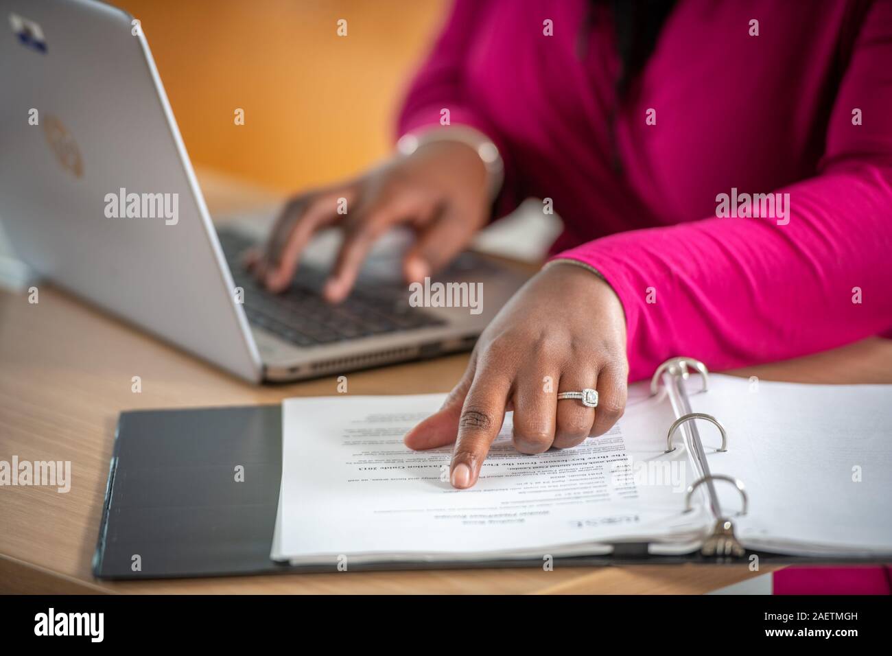 A worker checks some paperwork while they're on the computer Stock Photo