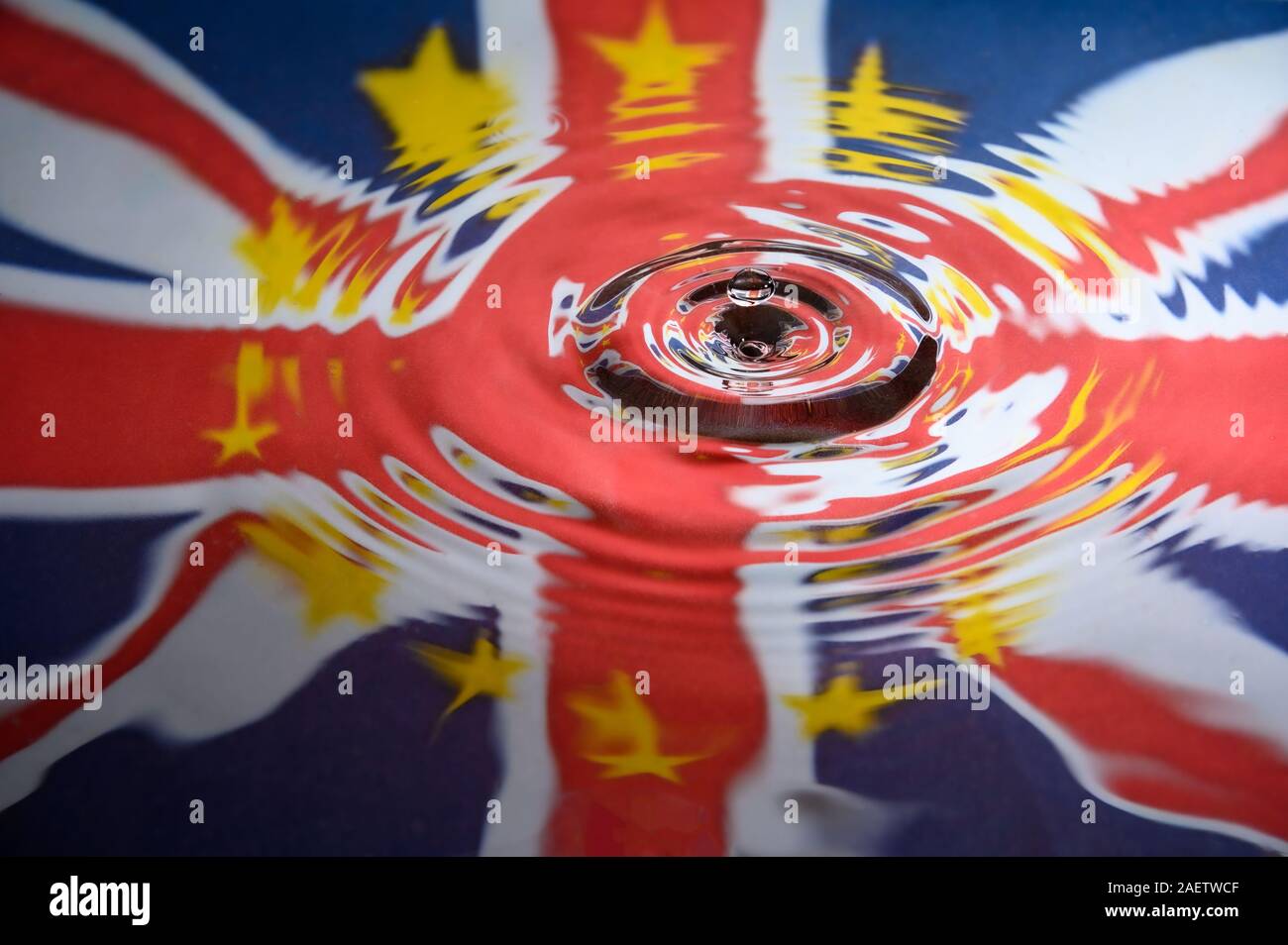 UK Union Jack and the stars of the European Union reflected in a water splash with a single drop of water about to land. Abstract Brexit background. Stock Photo