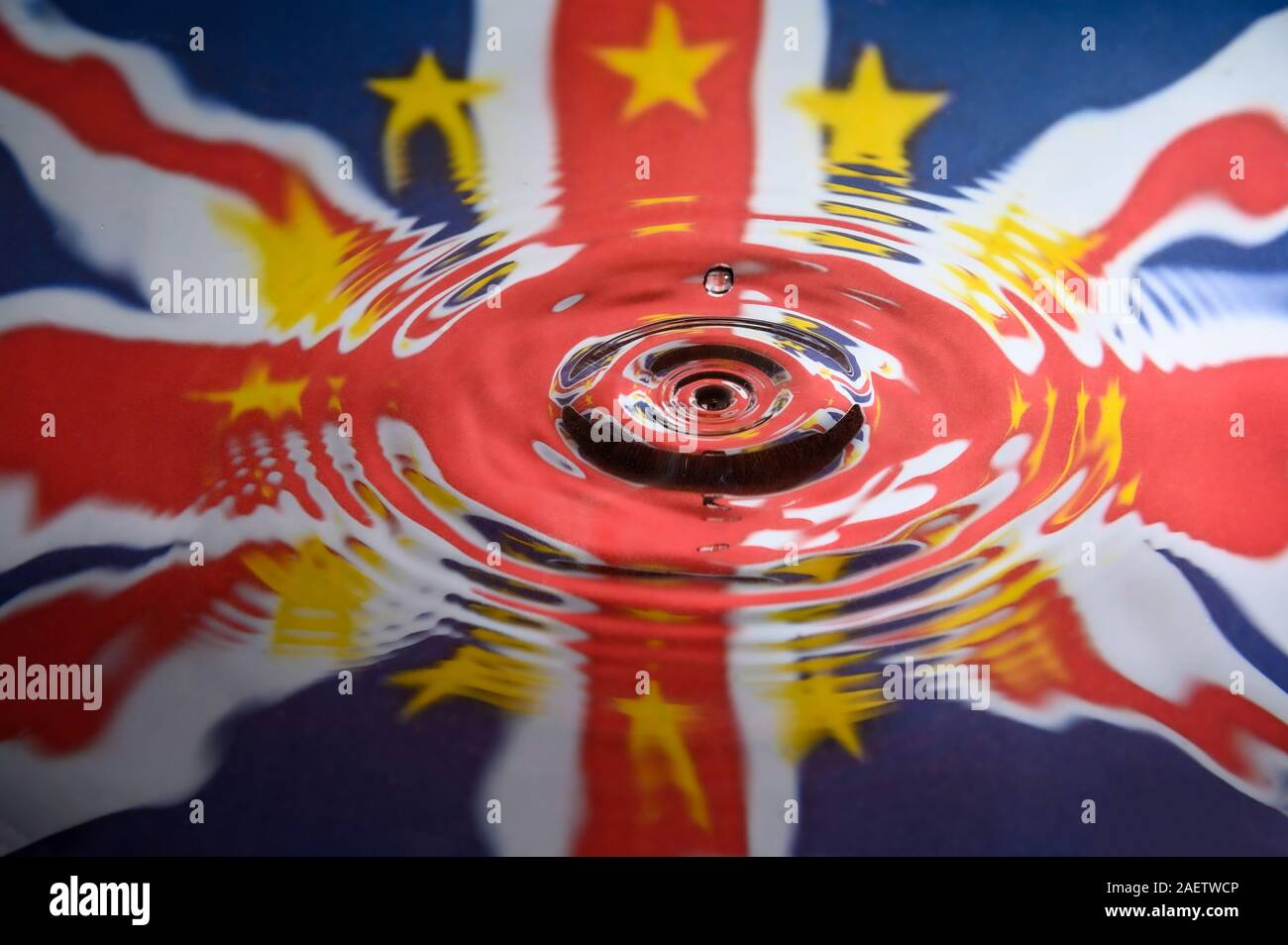 UK Union Jack and the stars of the European Union reflected in a water splash with a single drop of water falling. Abstract Brexit background. Stock Photo