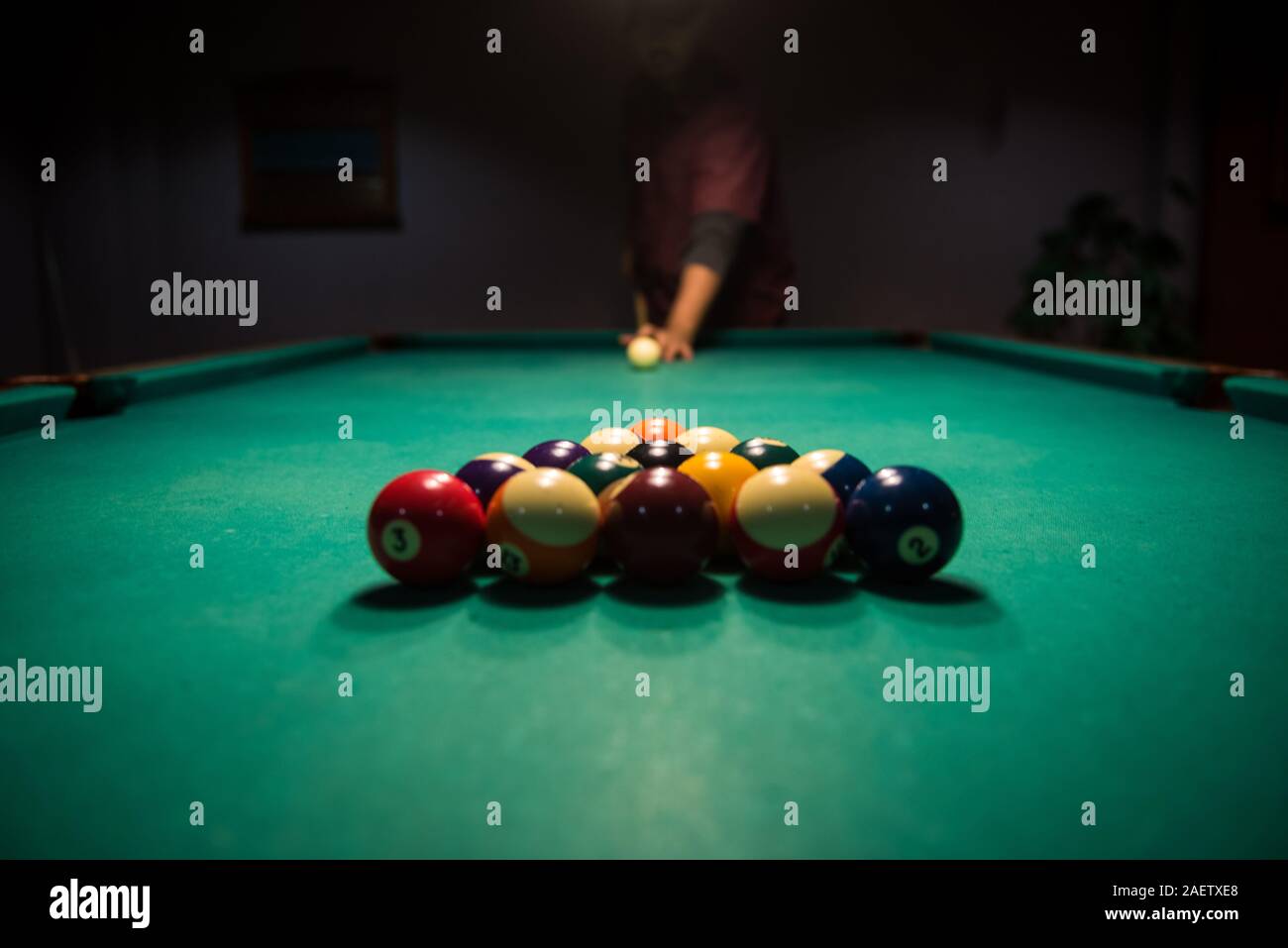 Male lines up billiard shot to sink a ball by the corner pocket Stock