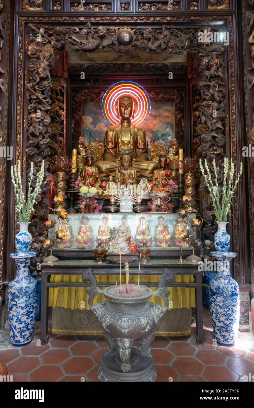 An altar including offerings and a golden Buddhist statue inside a pagoda  in southern Vietnam Stock Photo - Alamy