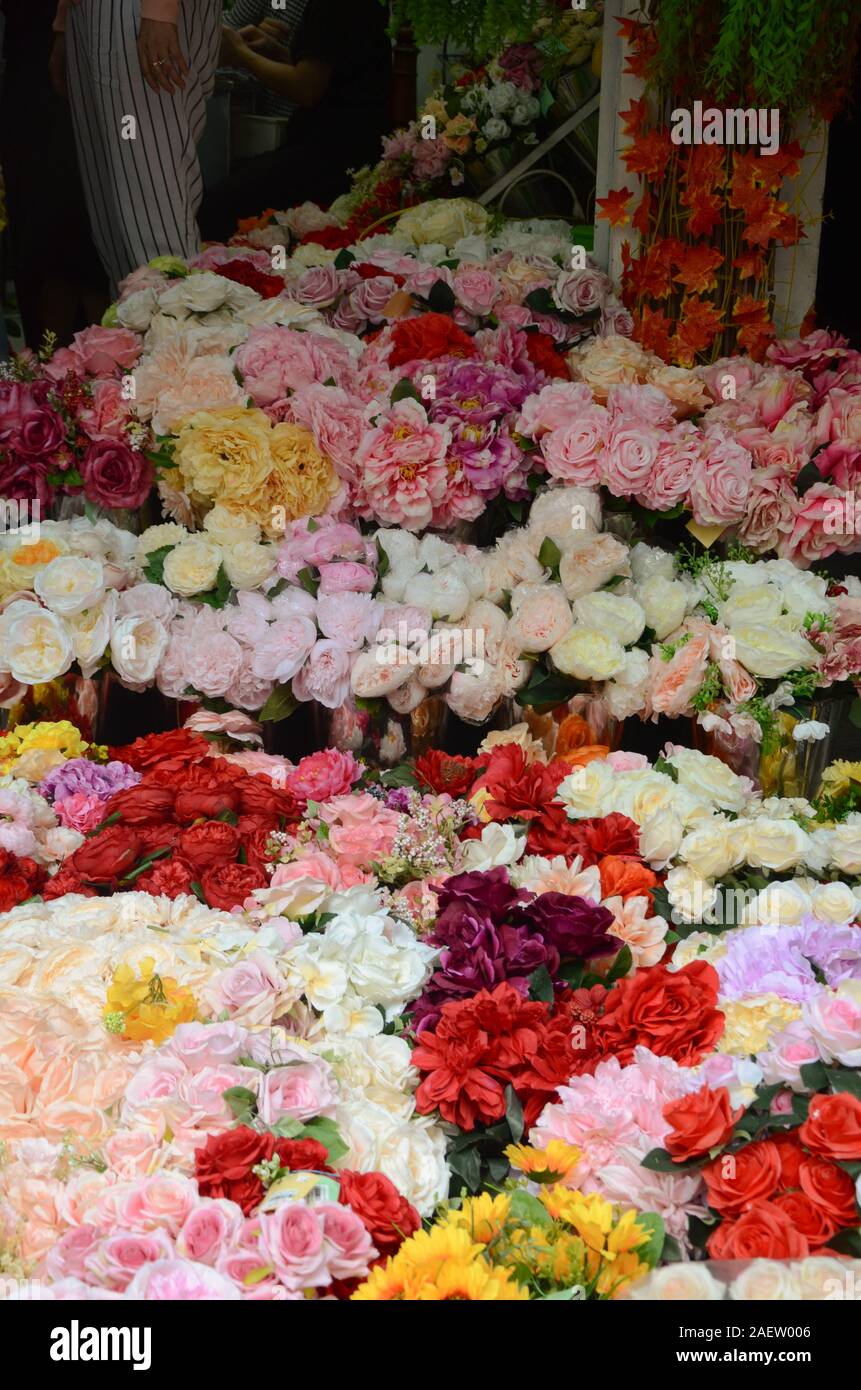 Bouquets of roses and other flowers wait to be purchased outside of a