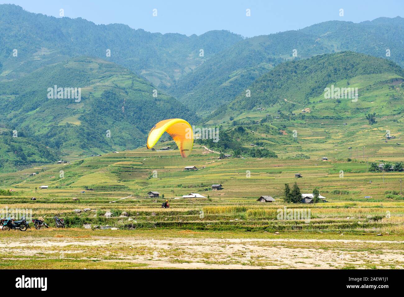 Paraglider flies over the green, brown, yellow and golden rice terrace fields of Tu Le valley, Northwest of Vietnam Stock Photo