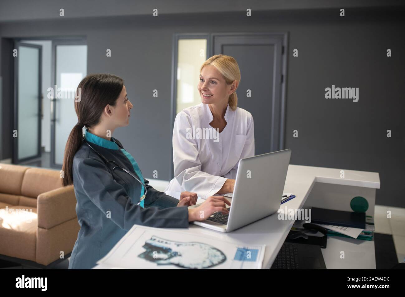 Young female intern and blond doctor sitting at the table Stock Photo