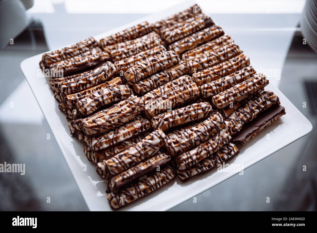 Shortbread cookies, drizzled with chocolate lying on a white, square plate. Stock Photo