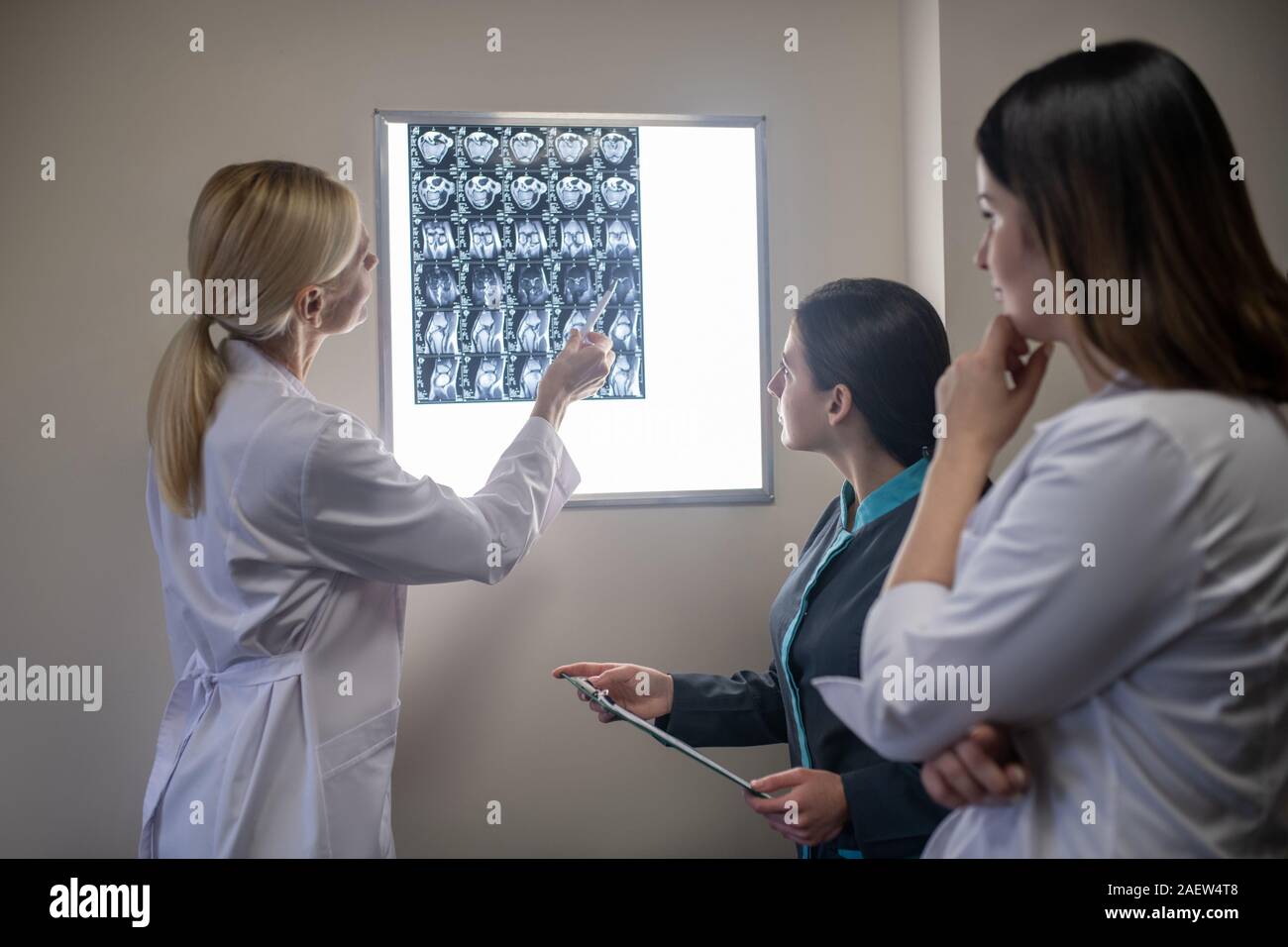 Blond doctor showing mri scan to her colleagues Stock Photo