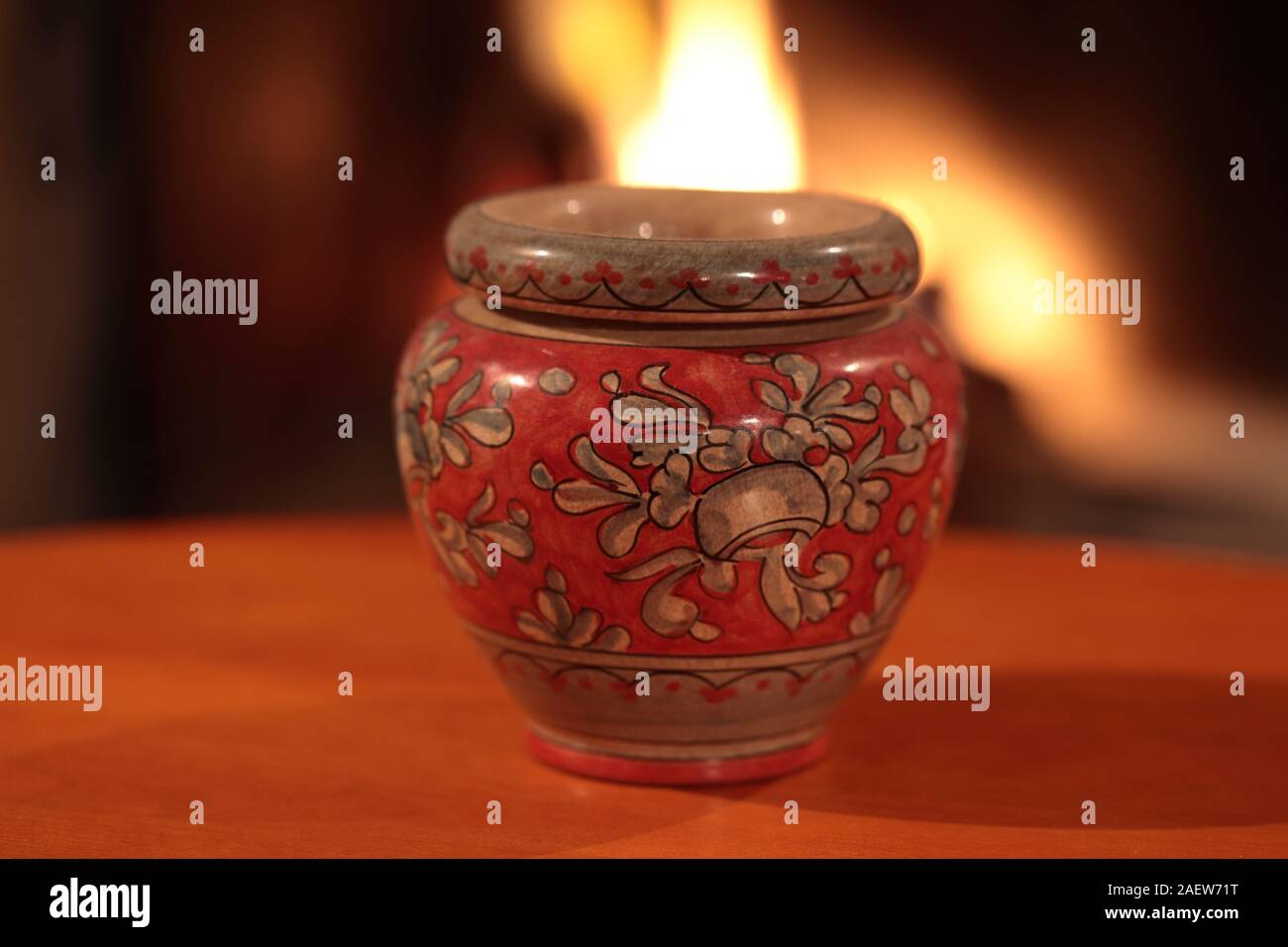 Red vase decorated with fireplace in the background Stock Photo