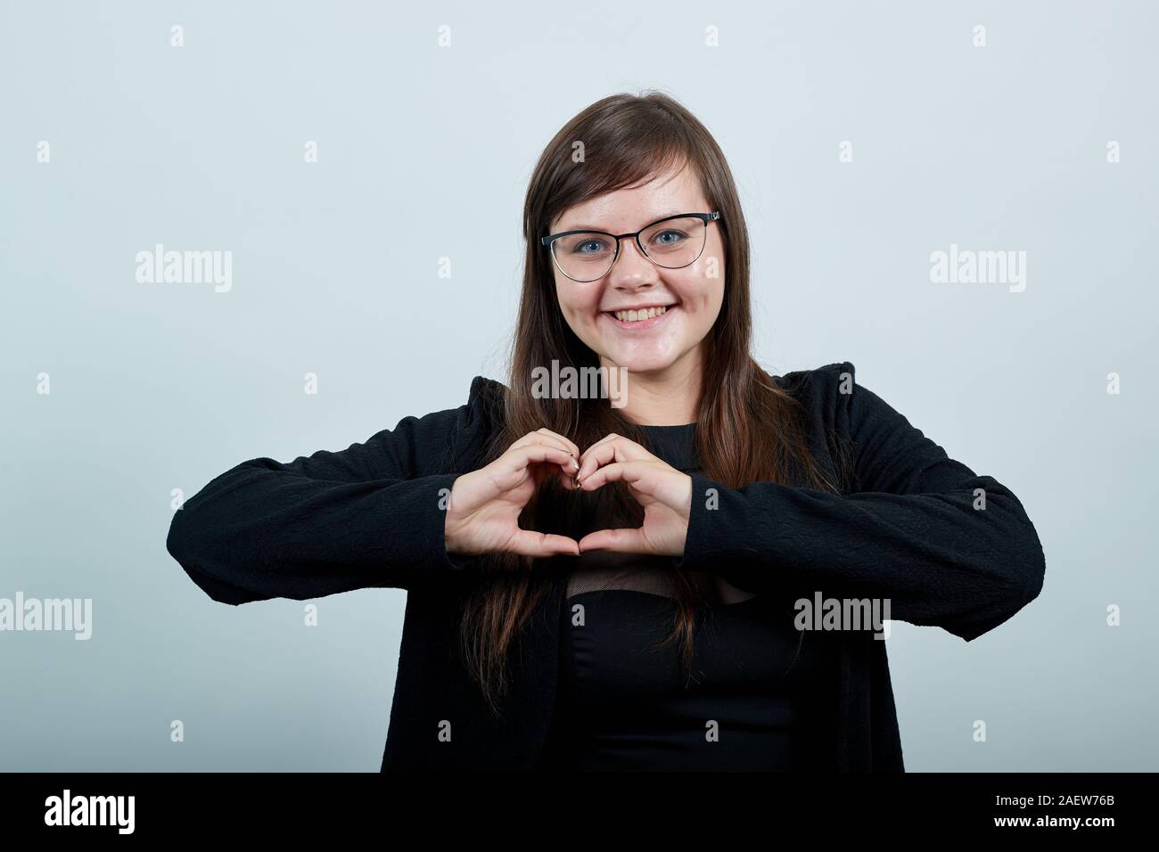 Young attractive caucasian woman in nice clothes showing shape heart with hands Stock Photo