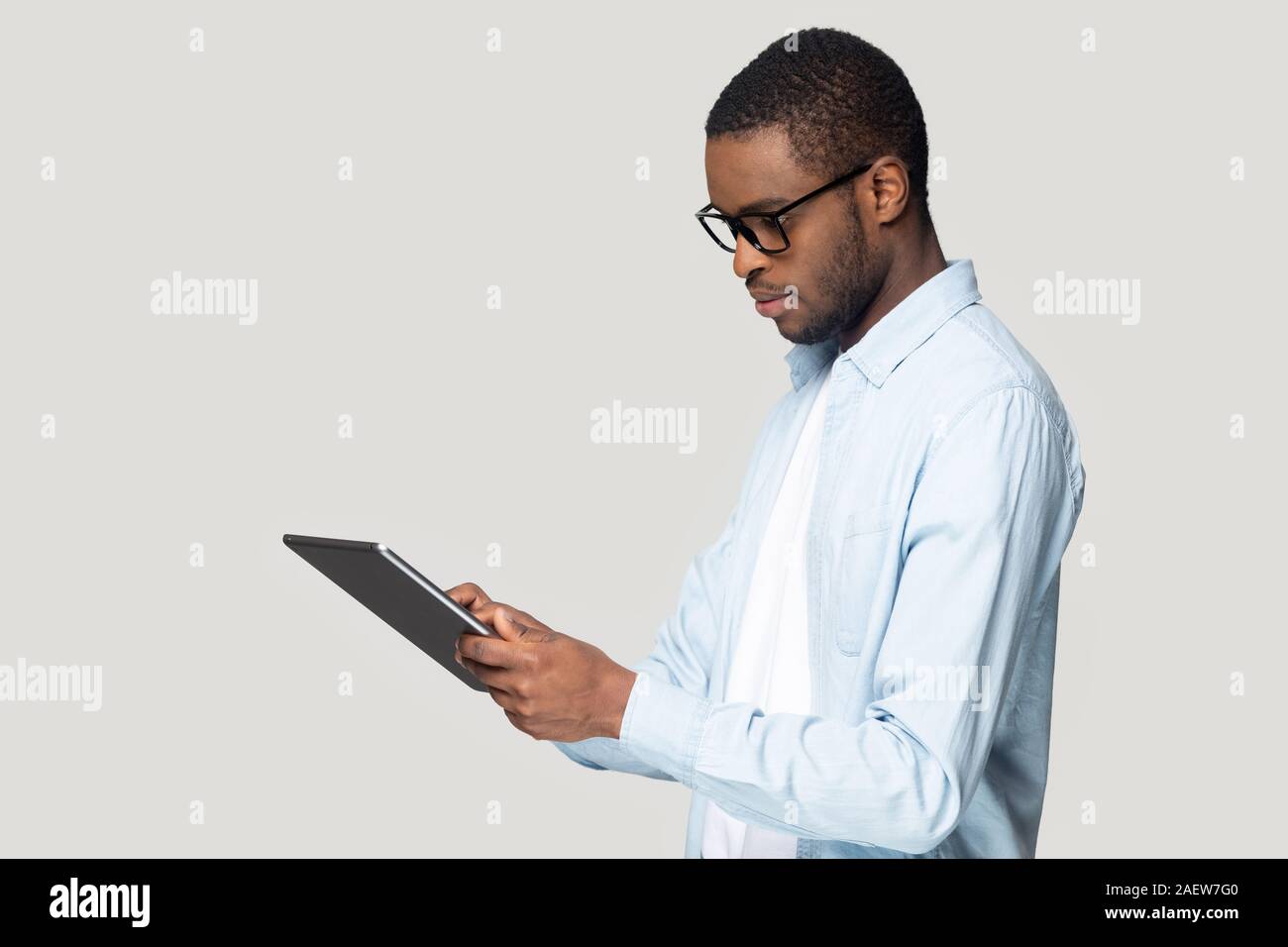 Side view young thoughtful african american guy holding digital tablet. Stock Photo