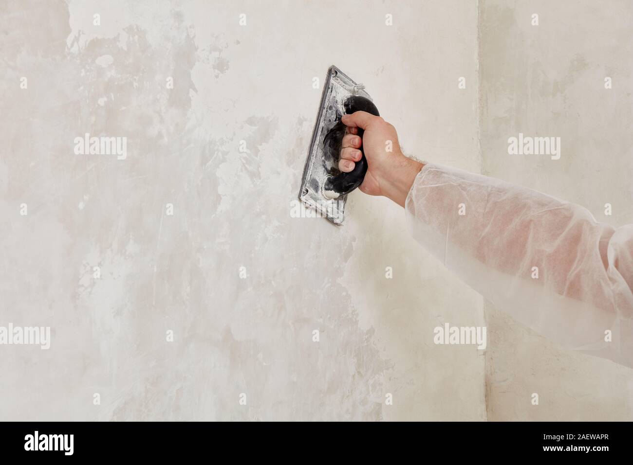 Hand of a man sanding a wall after plastering Stock Photo