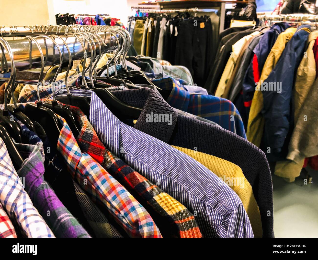 Used clothes on hangers in second hand Stock Photo - Alamy