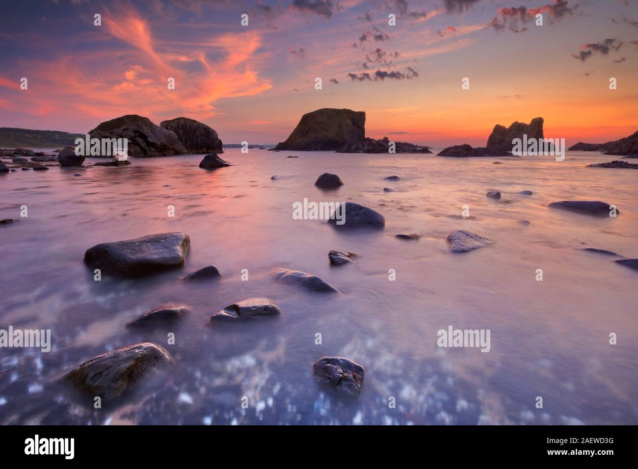 Sea stacks and natural arch along the coast near Ballintoy Harbour on the Causeway Coast of Northern Ireland at sunset. Stock Photo