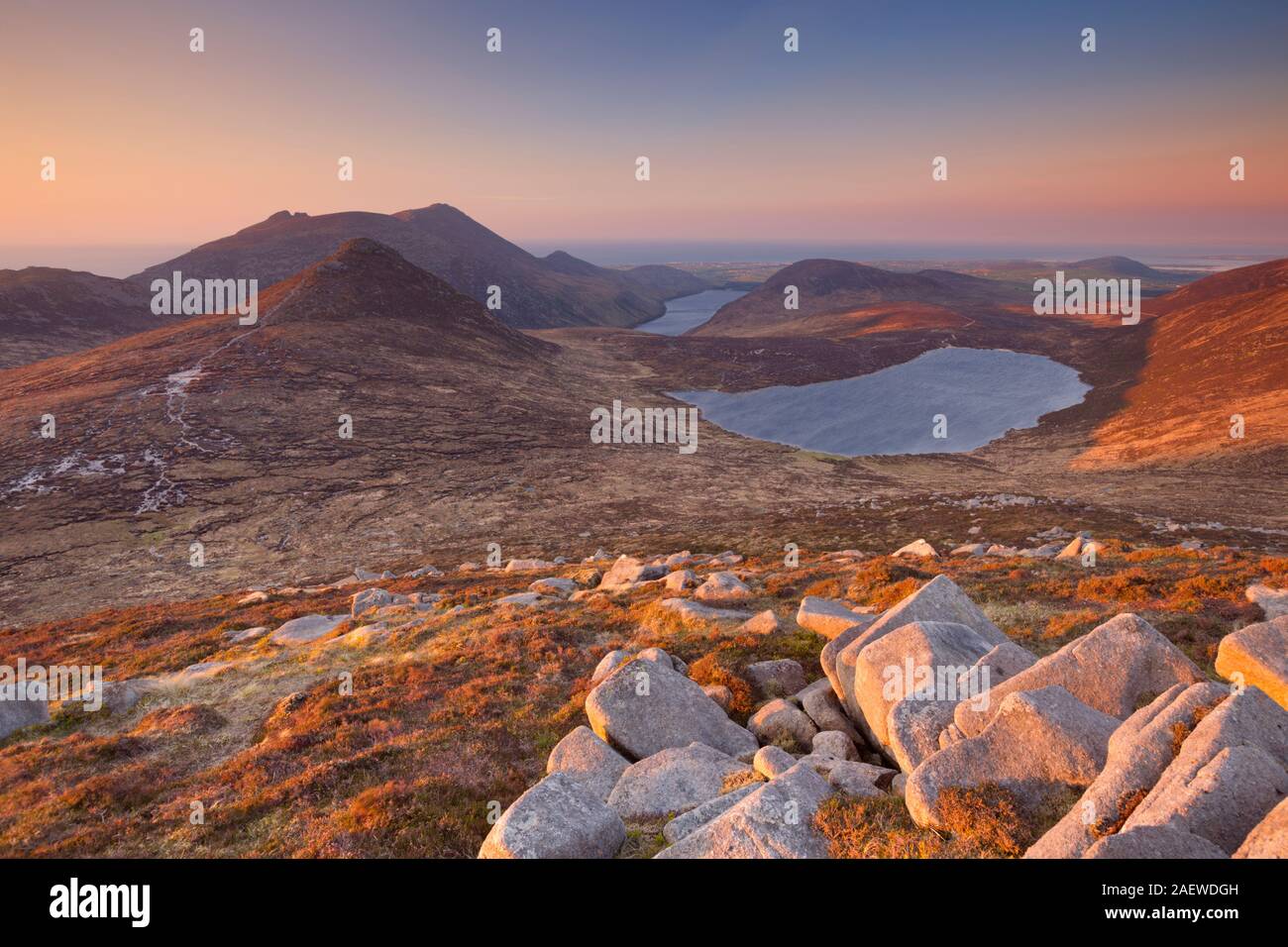 Sunrise over the Mourne Mountains and lakes in Northern Ireland. Photographed from the peak of Slieve Loughshannagh. Stock Photo