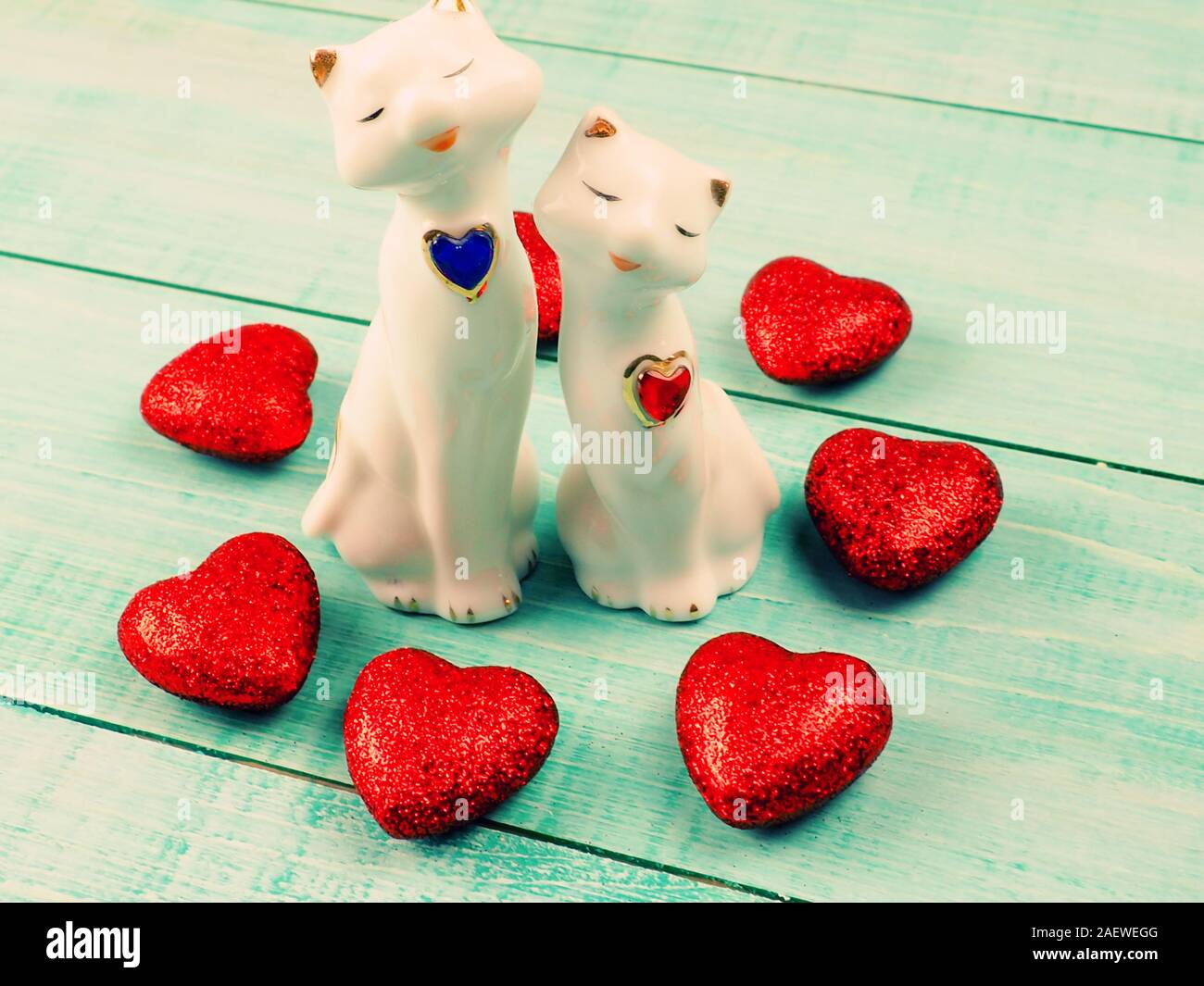 Greetings. Figurines of two cats with little red hearts on a blue