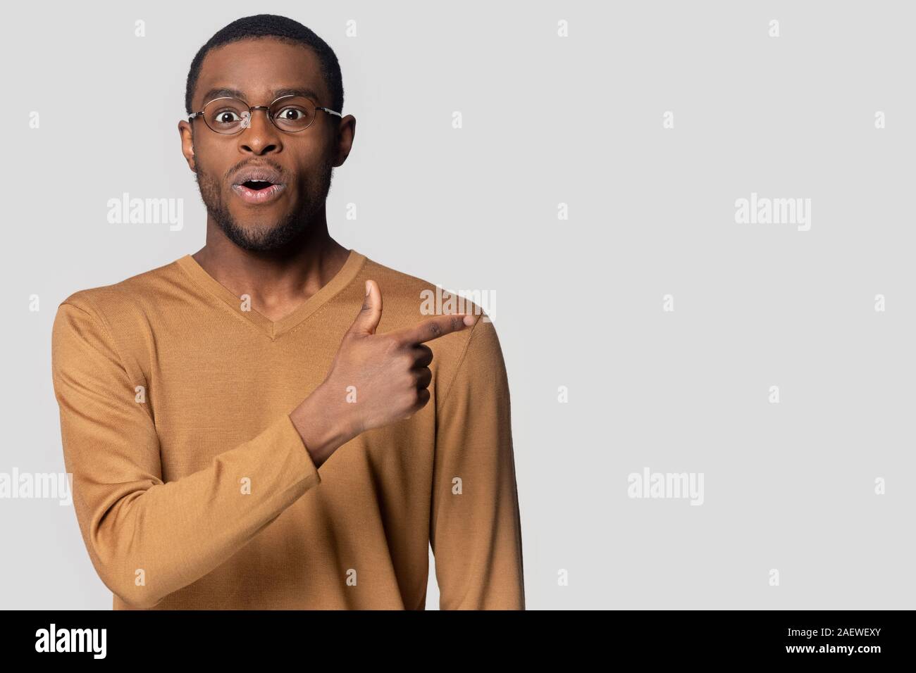 Surprised black guy pointing finger aside on empty copy space. Stock Photo