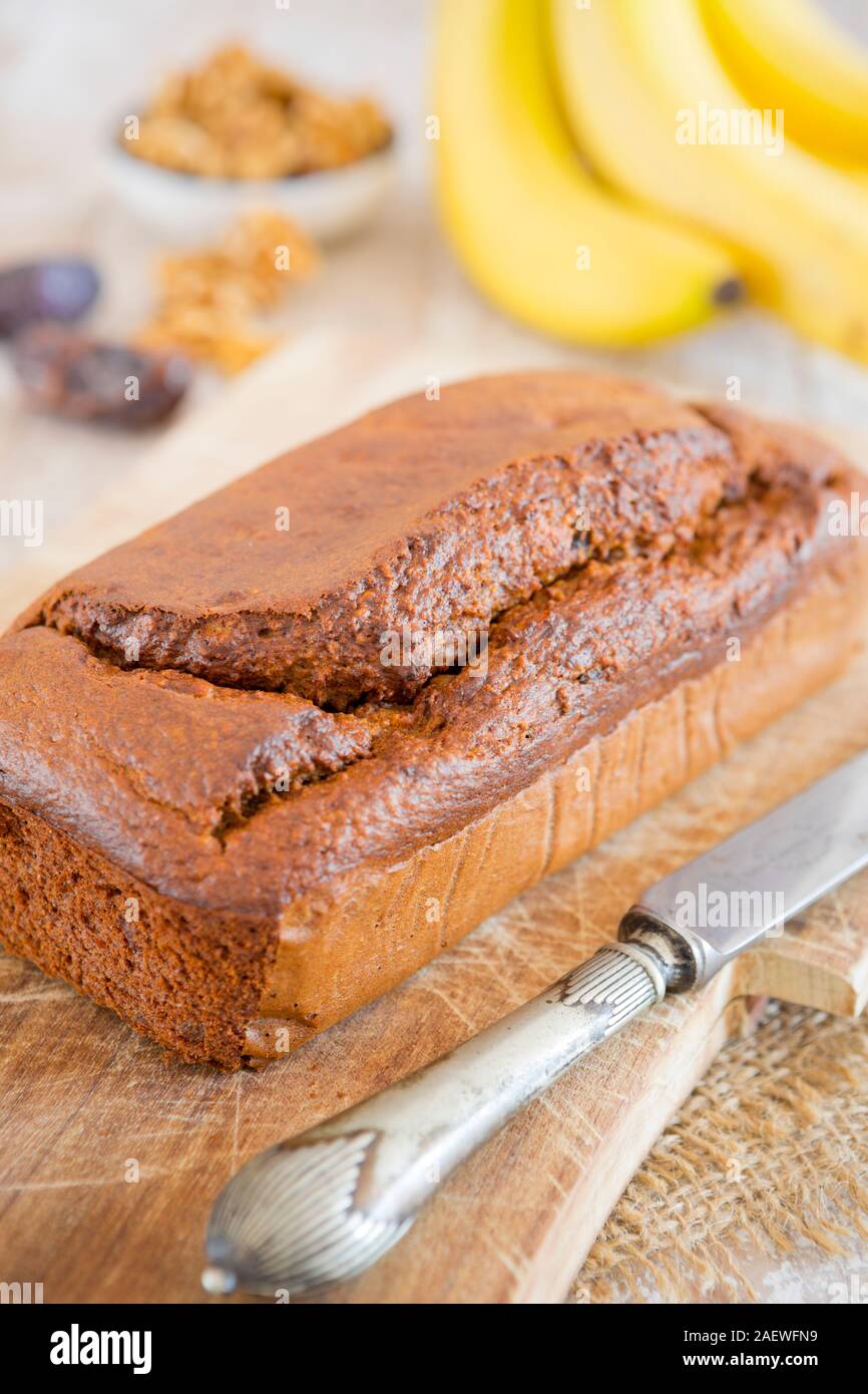 Homemade banana bread with walnuts and dates on a rustic table. Stock Photo