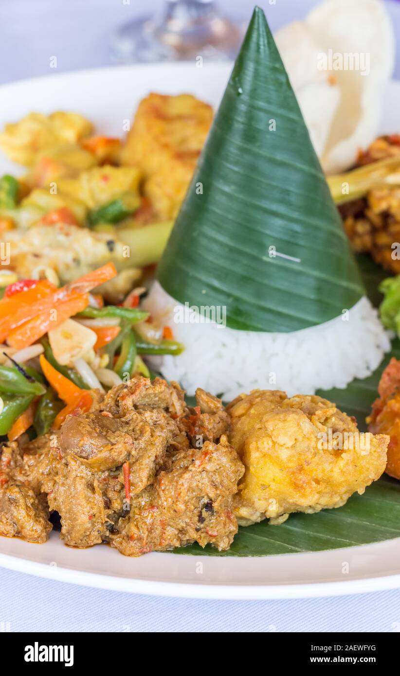 Nasi Campur Bali with tempeh, chicken and vegetables, served on a banana leaf Stock Photo