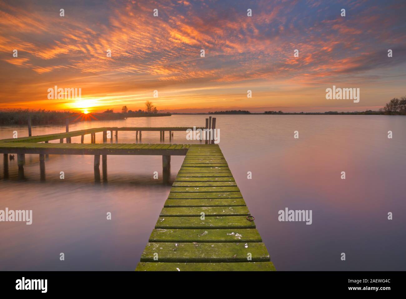 An old jetty on a lake in The Netherlands, photographed at sunset. Stock Photo