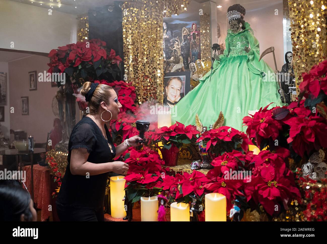 A transgender Santa Muerte priestess leads a service in her home temple in Jackson Heights, Queens, NYC. She blows smoke at a deity as is a custom. Stock Photo