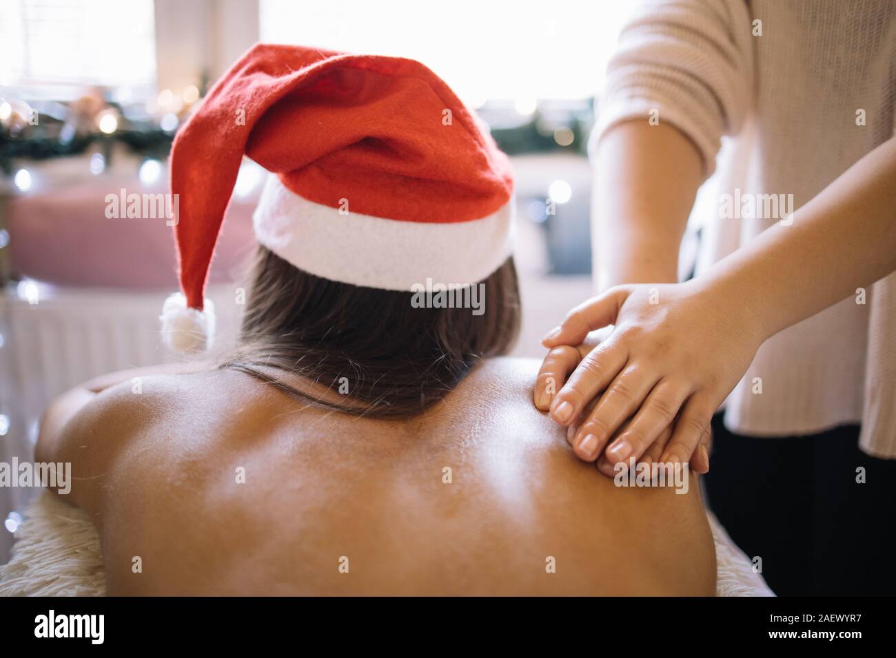 Woman with Santa hat having massage from masseuse. Masseuse massaging  woman's back in Christmas decorated SPA saloon, with copyspace, close-up.  Ideal Stock Photo - Alamy